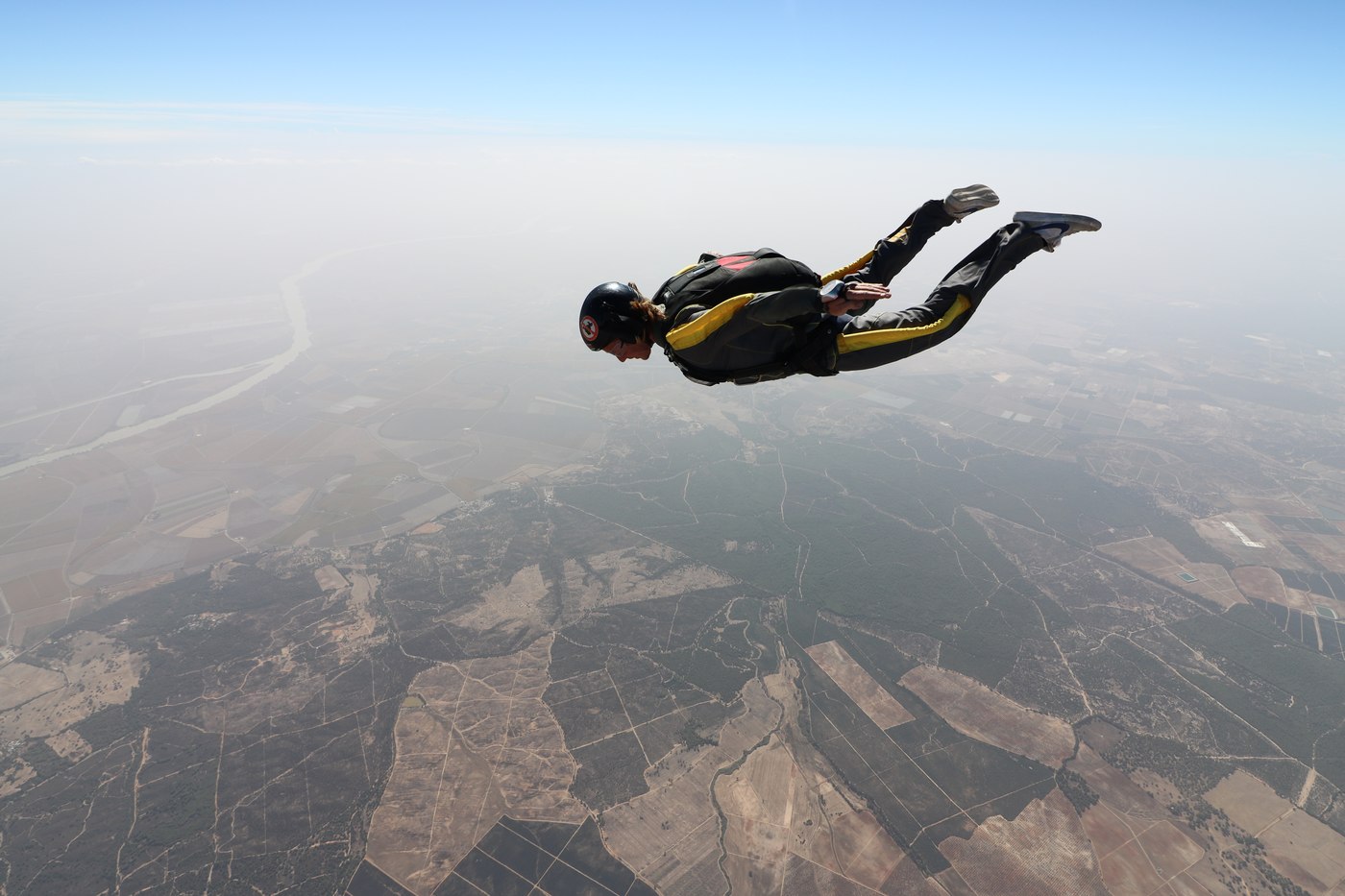 Jaro skydiving high above farmland, up in the air