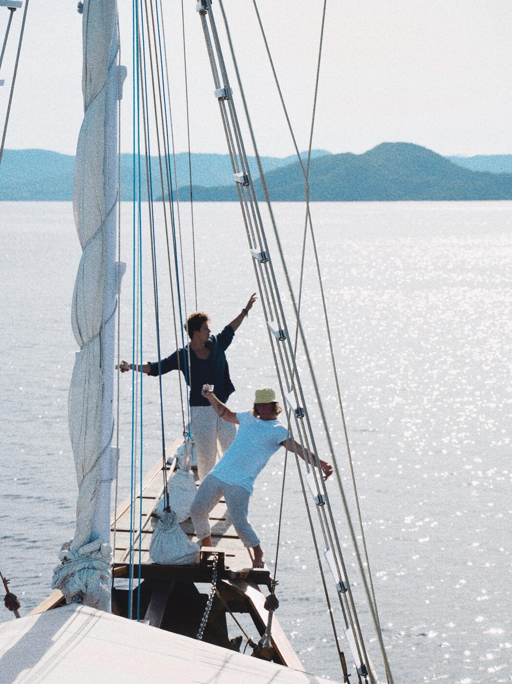 Two travelers celebrating on the deck of a sailboat at sea