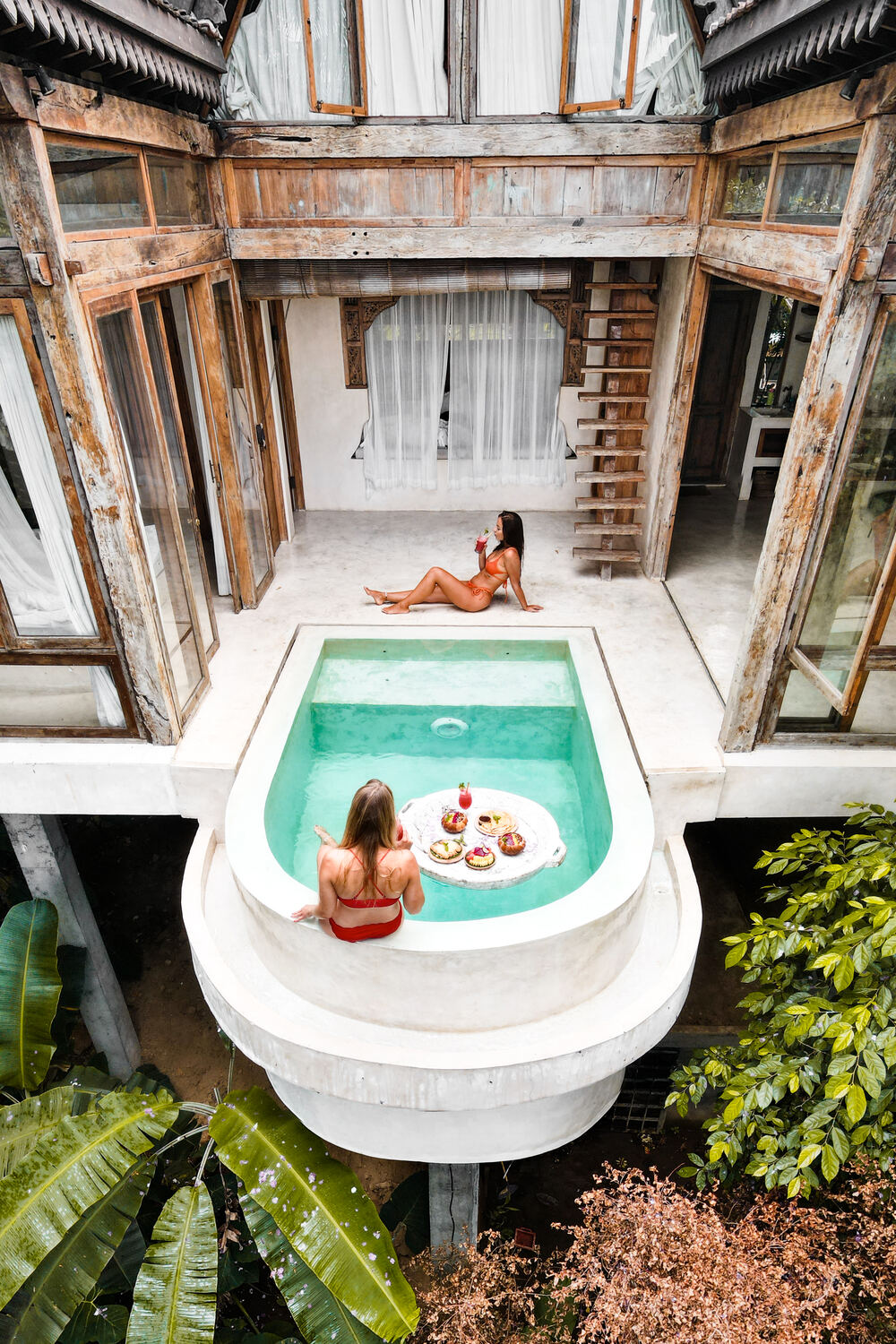 Two women relaxing at a boutique pool overlooking a jungle villa