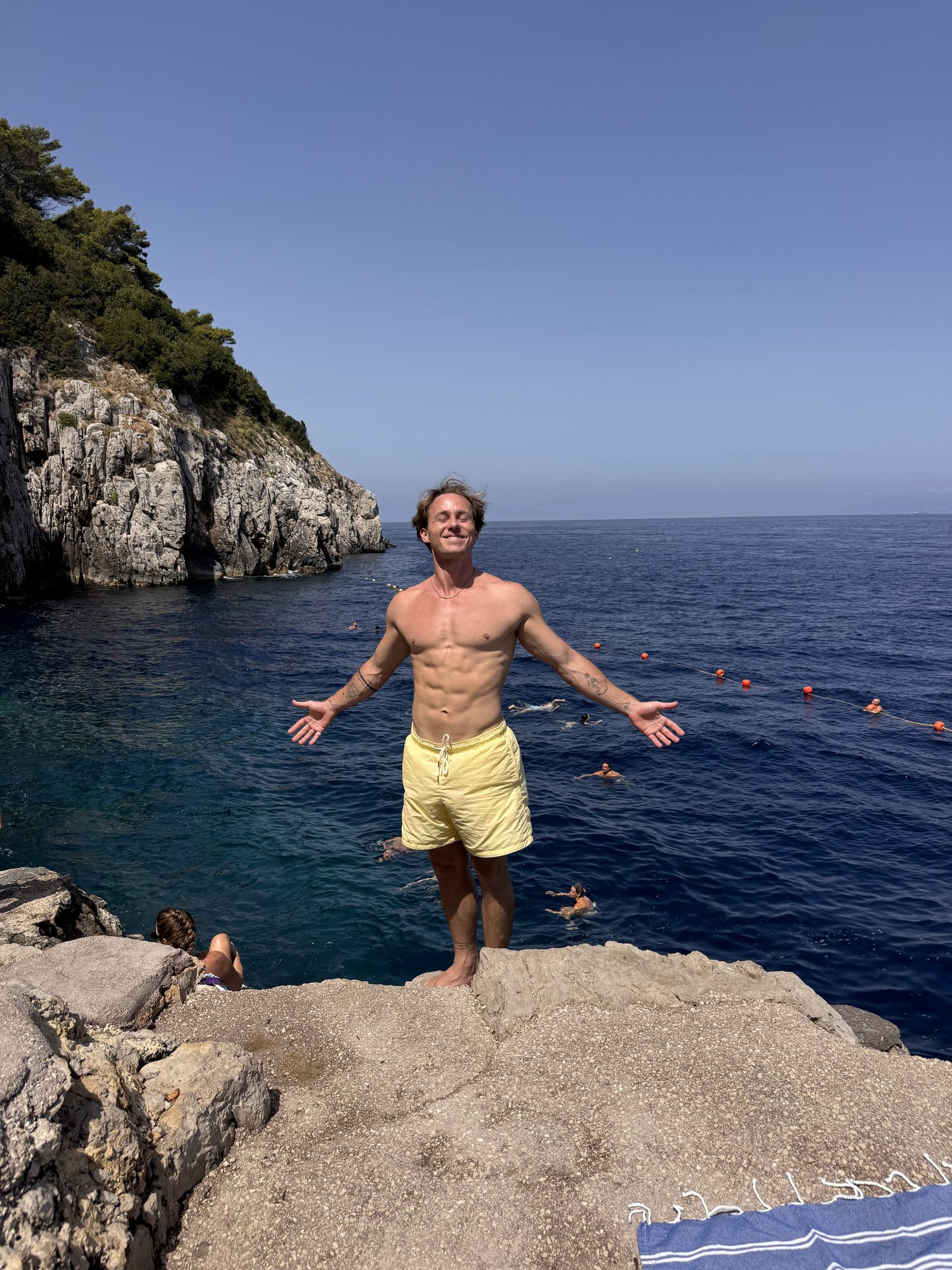 Jaro jumping off a cliff into turquoise water